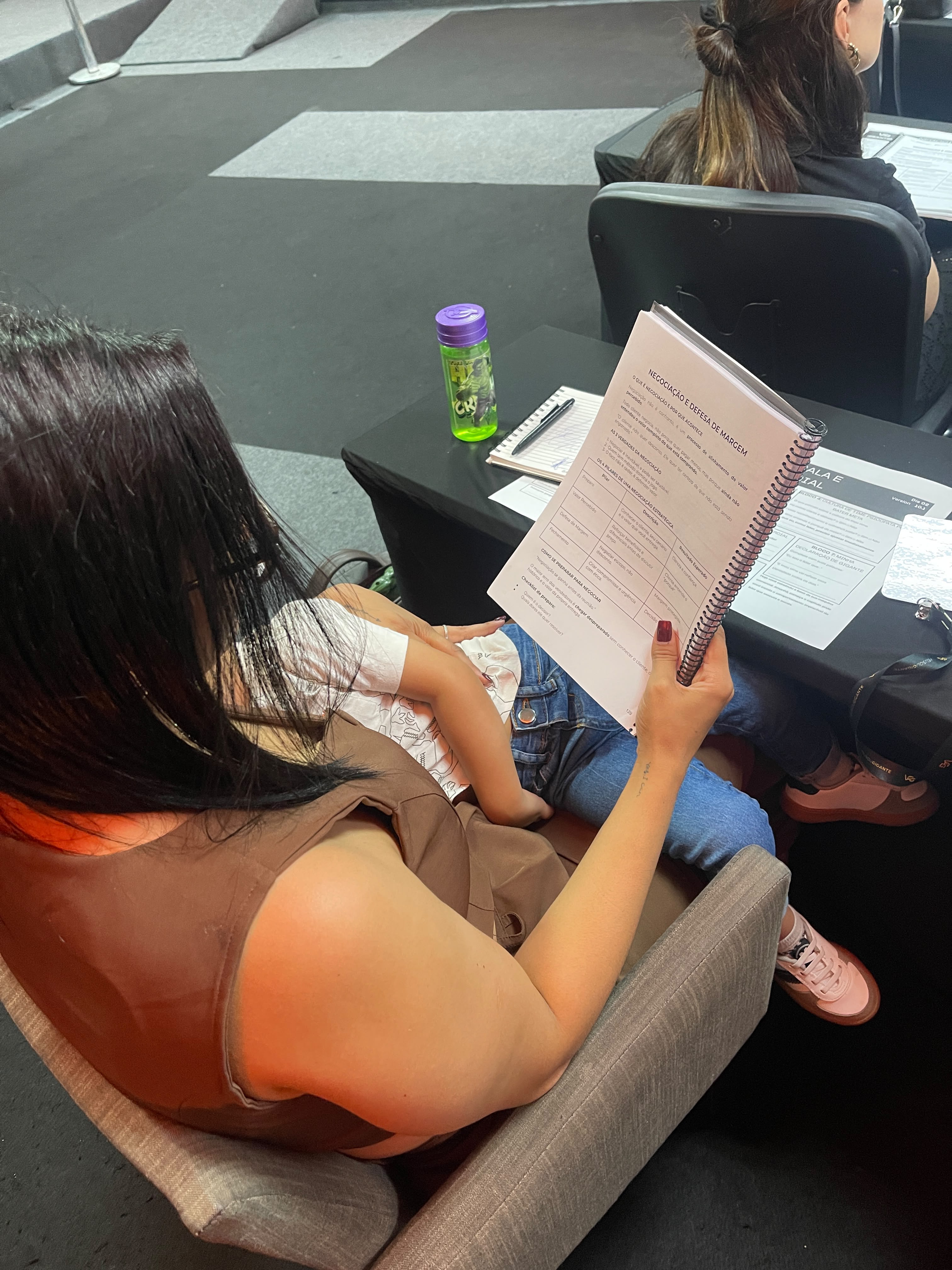 Letícia estudando material de negociação comercial com o filho no colo